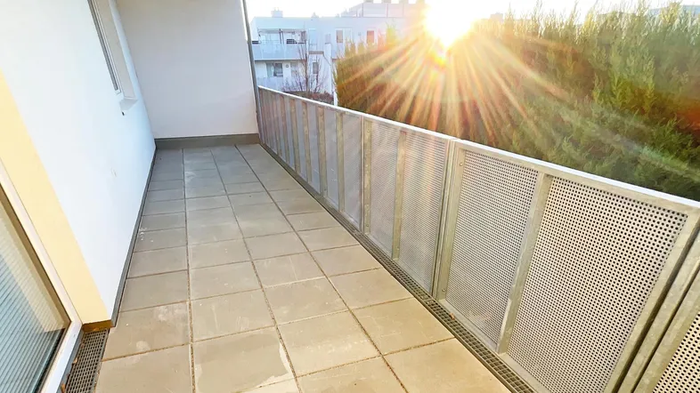 Sonniger Balkon mit Fliesenboden und moderner Metallbrüstung, ideal für entspannte Stunden im Freien.