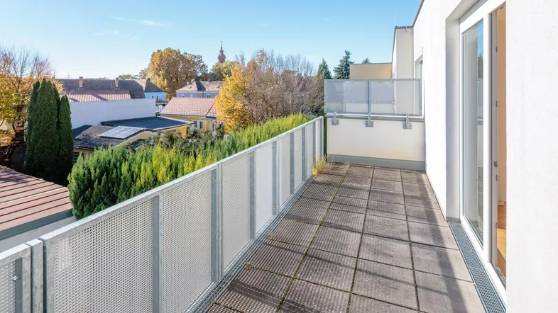 Geräumiger Balkon mit Fliesenboden und weitem Blick über die grüne Umgebung.