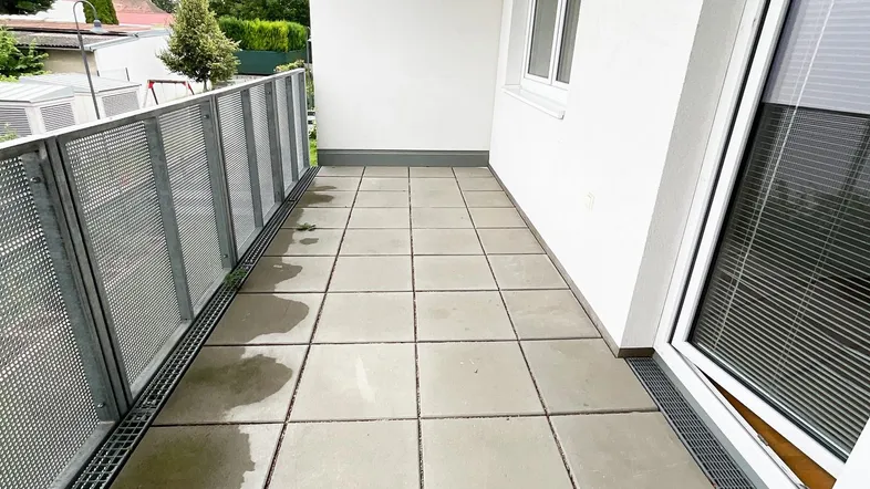Geräumiger Balkon mit Fliesenboden und Metallgeländer, ideal für entspannte Stunden im Freien.