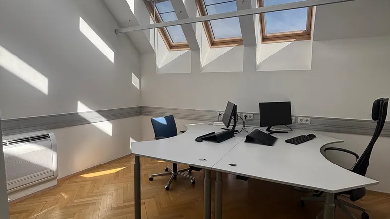 Helles Büro mit schrägen Decken, mehreren Dachfenstern und elegantem Fischgrätparkettboden.