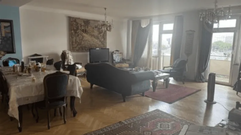 Geräumiger Wohn- und Essbereich mit Parkettboden, Kronleuchtern und Zugang zu einem Balkon.