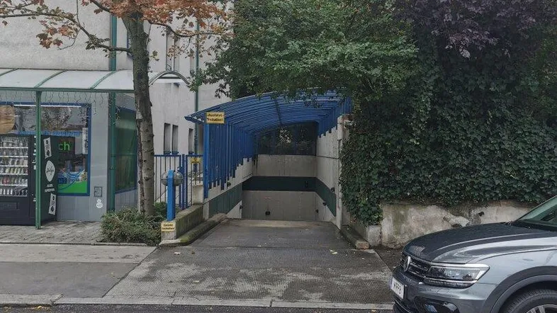 Einfahrt zur Tiefgarage von der Straße aus gesehen, mit einem geparkten Auto daneben.
