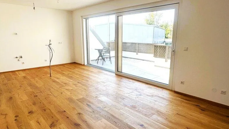 Helles Wohnzimmer mit Holzboden und Zugang zu einer großen Terrasse.