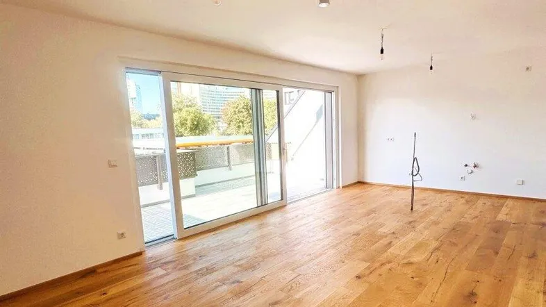 Helles Wohnzimmer mit Echtholzparkett und Zugang zu einer großzügigen Terrasse.