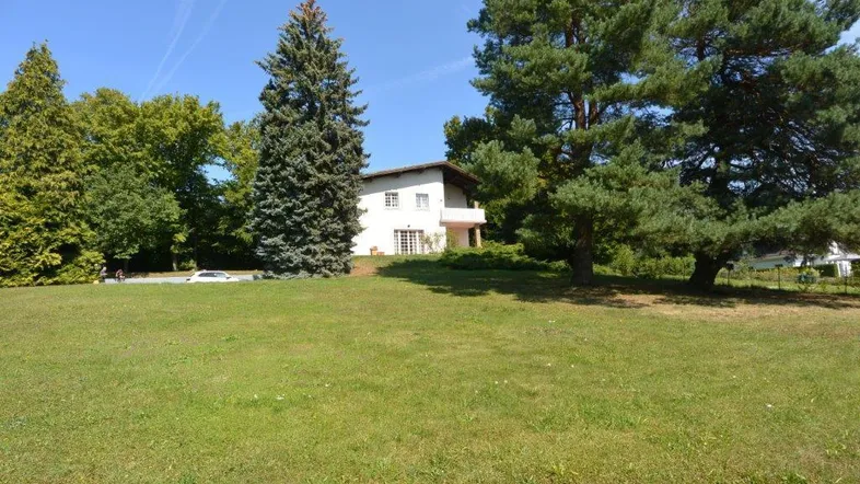 Großzügiges Grundstück mit viel Grünfläche und einem freistehenden Haus im Hintergrund.