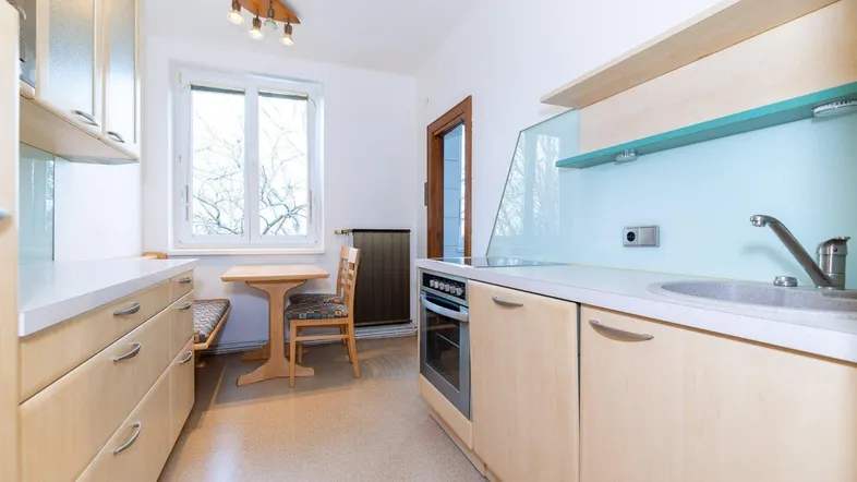 Helle Küche mit funktionalen Holzschränken, Essbereich am Fenster und integrierten Geräten.