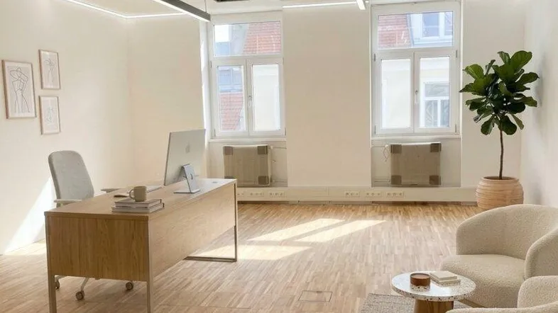 Helles und modernes Büro mit Holzfußboden, großen Fenstern und minimalistischer Einrichtung, ideal für produktives Arbeiten.