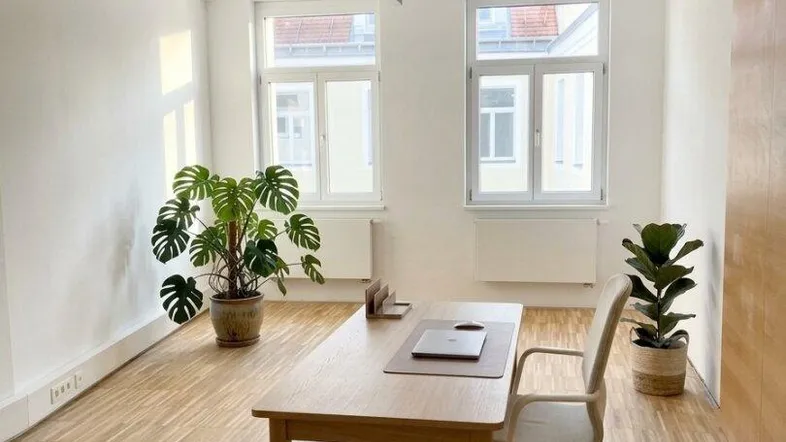 Helles und geräumiges Büro mit Holzboden, großen Fenstern und moderner Deckenbeleuchtung.