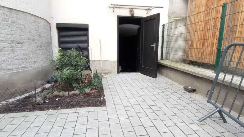 Gepflasterter Innenhof mit kleiner Grünfläche und offenem Eingangsbereich zum Gebäude.