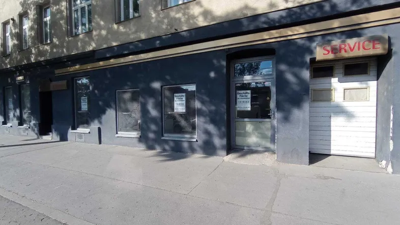 Fassade eines Geschäftsgebäudes mit mehreren Schaufenstern und einem "Service"-Schild an der Straßenseite.
