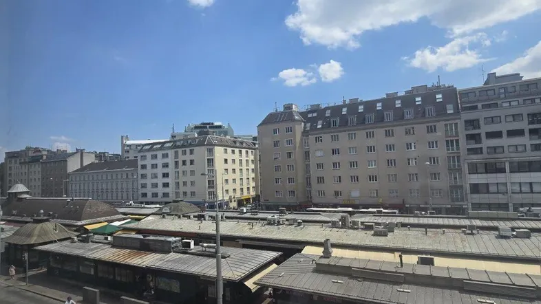 Blick auf die Stadt mit Gebäuden und einer Straße unter einem blauen Himmel mit Wolken.