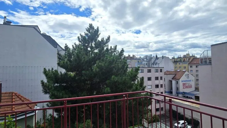 Geräumiger Balkon mit Fliesenboden und rotem Geländer, bietet einen Blick auf die umliegende Stadt.