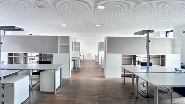 Großes, modernes Großraumbüro mit mehreren Arbeitsplätzen, Holzfußboden und abgehängter Decke.