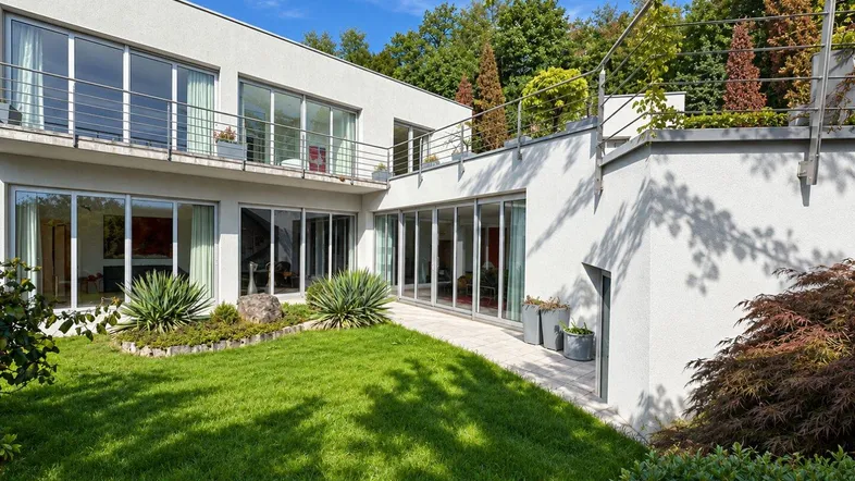 Moderne Villa mit gepflegtem Garten, großer Rasenfläche und sonnigen Terrassenbereichen.