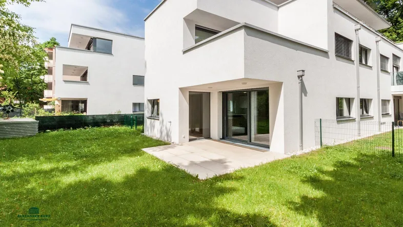 Moderne Wohnanlage mit weißer Fassade, Terrasse und angrenzendem Gartenbereich.