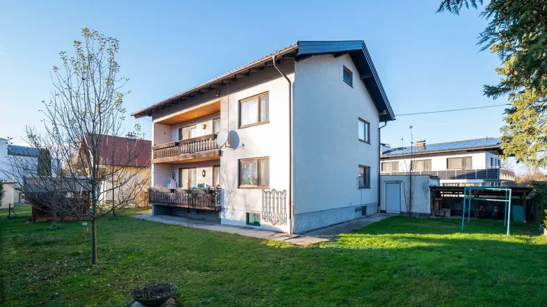 Einfamilienhaus mit großem Garten, Balkonen und gepflegter Fassade in sonniger Umgebung.