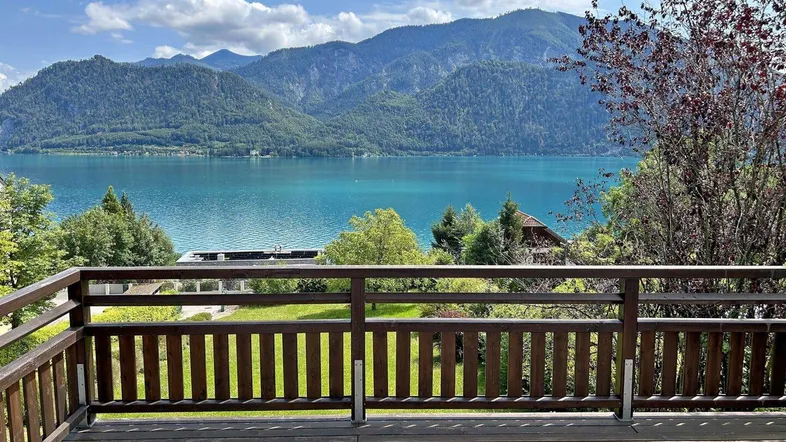 Geräumiger Holzbalkon mit atemberaubendem Blick auf den See und die umliegenden Berge.