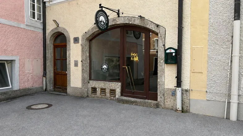 Historische Fassade eines Geschäftsgebäudes mit großen Schaufenstern und Holztüren im Erdgeschoss.