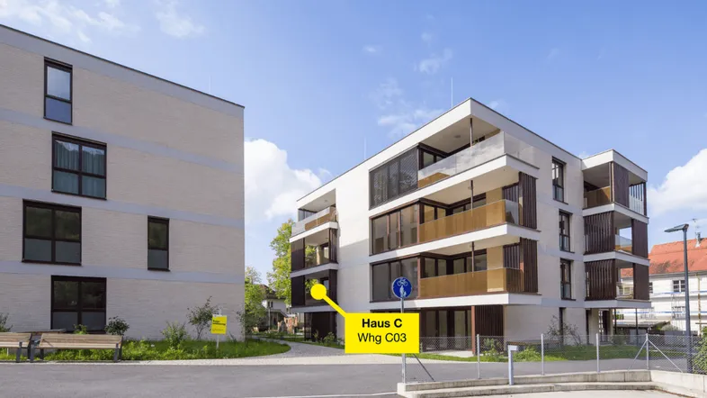 Moderne Mehrfamilienhäuser mit Balkonen und großen Fenstern in einer gepflegten Umgebung.