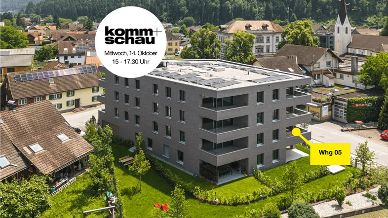 Luftaufnahme eines modernen Wohngebäudes mit Solarpaneelen auf dem Dach in einer grünen Umgebung.