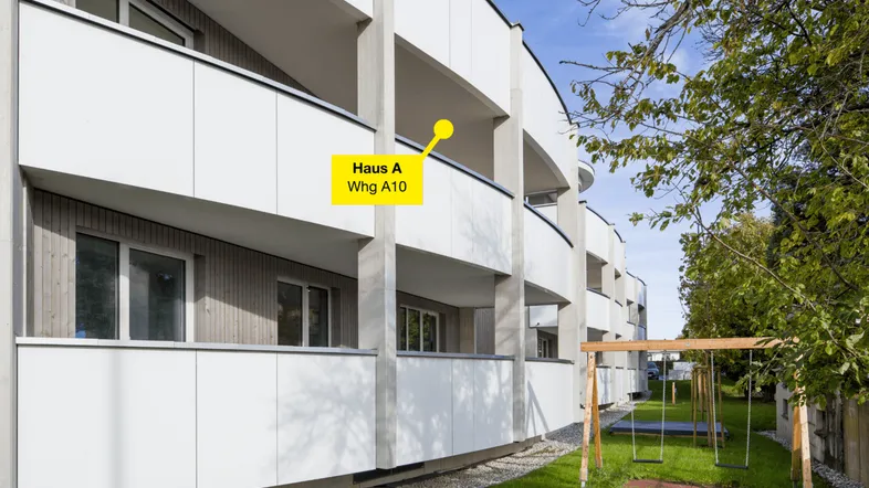 Moderne Wohnanlage mit geschwungener Fassade, Balkonen und einem Kinderspielplatz im grünen Außenbereich.