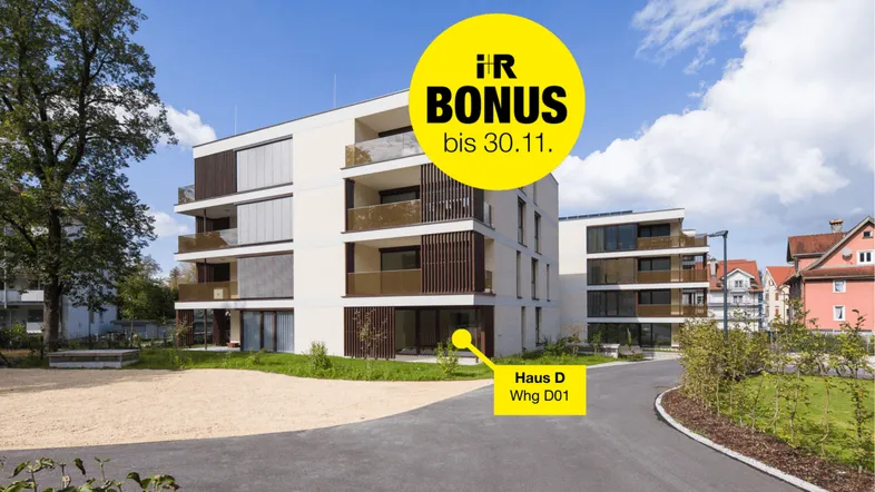 Modernes Mehrfamilienhaus mit Balkonen, großen Fenstern und gepflegten Grünflächen in sonniger Umgebung.