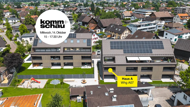 Luftaufnahme von zwei modernen Mehrfamilienhäusern mit Solaranlagen, umgeben von Grünflächen und einem Spielplatz.