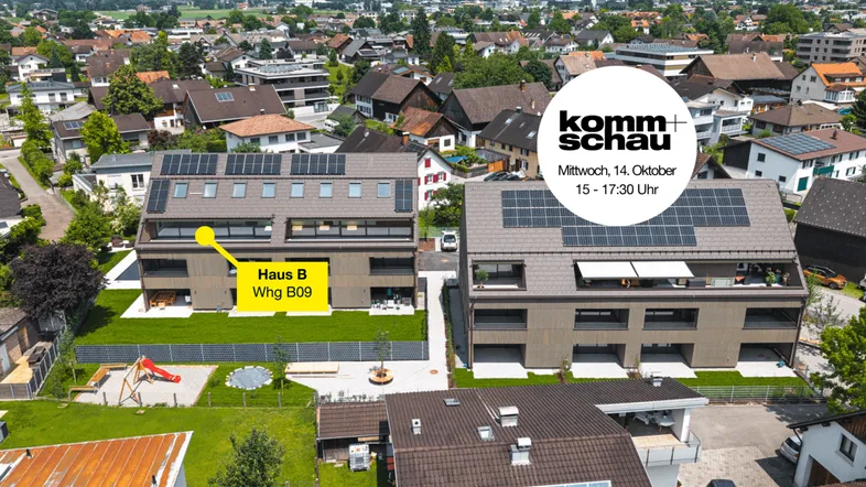 Luftaufnahme moderner Mehrfamilienhäuser mit Solaranlagen, Gemeinschaftsgarten, Spielplatz und Bergblick in einer Wohnsiedlung.