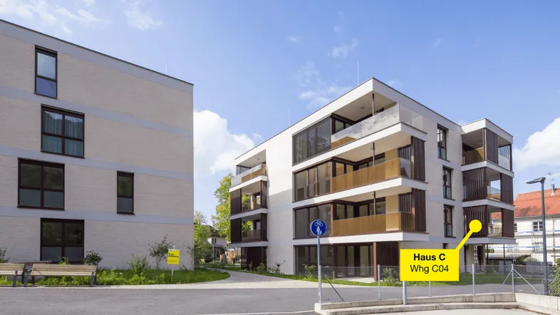Moderne Mehrfamilienhäuser mit Balkonen und zeitgenössischer Architektur unter blauem Himmel.