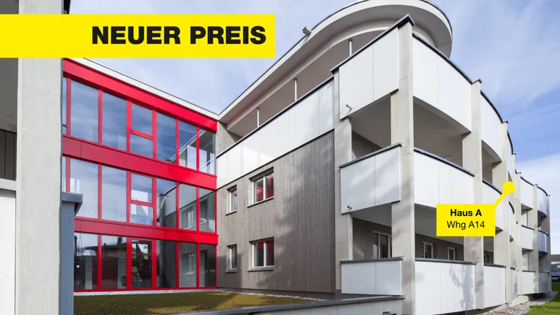 Moderne Wohnanlage mit markanten roten Fensterfronten, Holzverkleidung und mehreren Balkonen unter blauem Himmel.