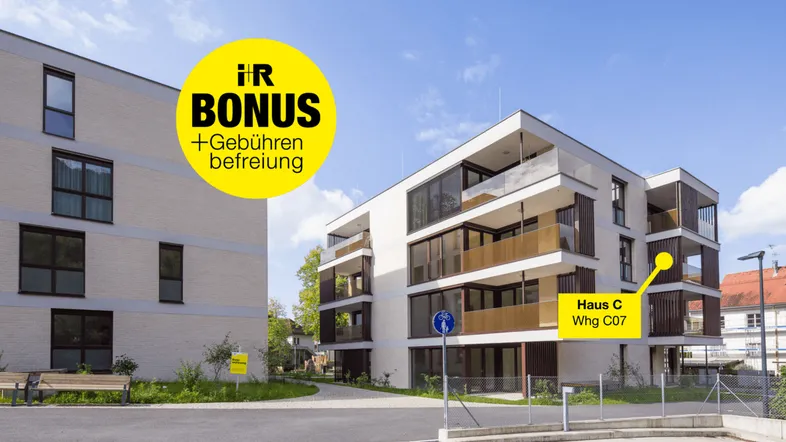 Moderne Mehrfamilienhäuser mit Balkonen und gepflegter Außenanlage unter blauem Himmel.