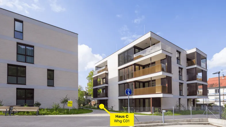 Moderne Wohngebäude mit klarer Architektur, großen Fenstern und Balkonen unter blauem Himmel.
