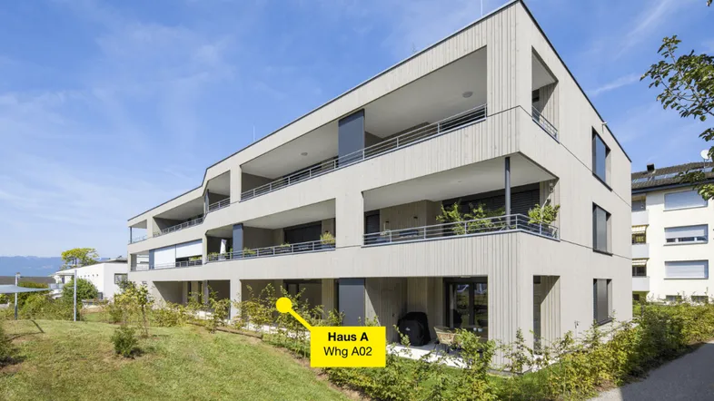 Modernes Mehrfamilienhaus mit Holzfassade, Balkonen und begrünten Außenbereichen in einer ruhigen Umgebung.