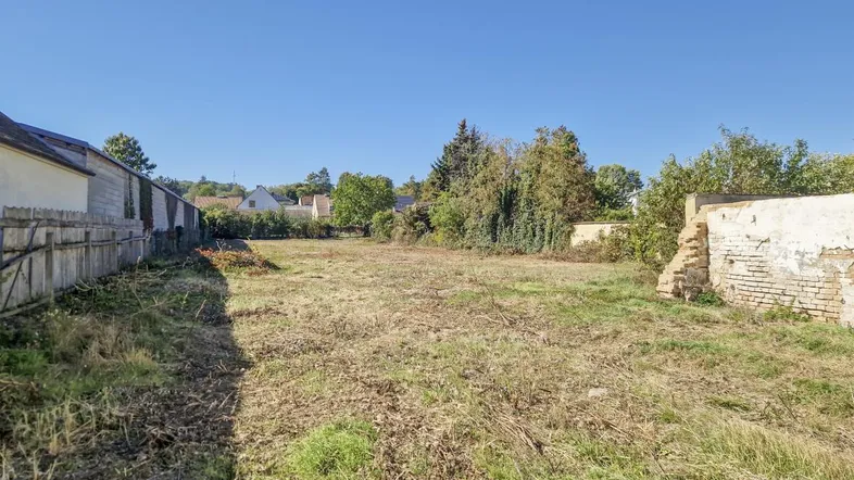Weitläufiges Grundstück mit Gras und umgebender Bebauung unter blauem Himmel.