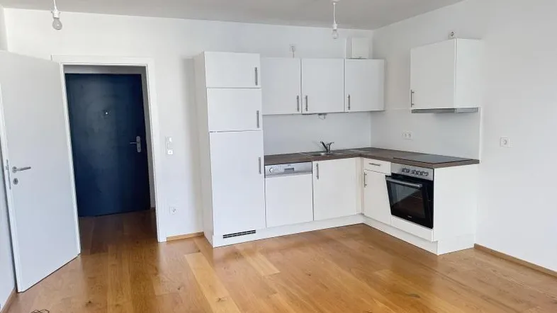 Helle offene Küche mit weißen Schränken, Holzboden und integrierten Geräten in einem modernen Wohnbereich.