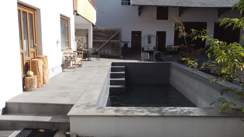 Außenbereich mit gepflasterter Terrasse, kleinem Pool und Sitzgelegenheiten im Freien.