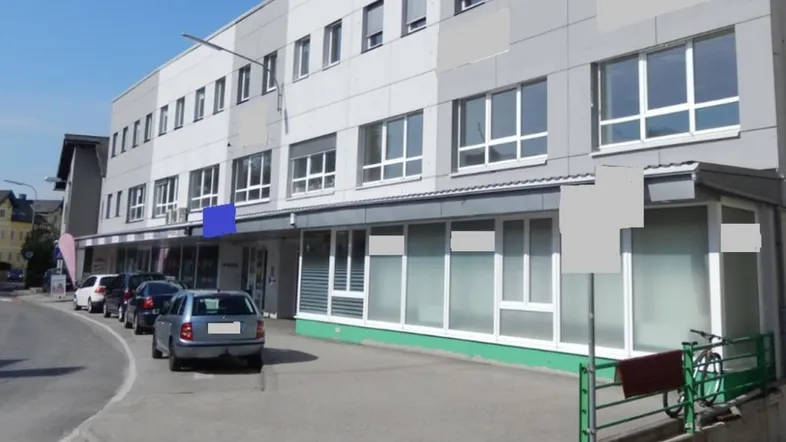 Ansicht eines modernen Geschäftsgebäudes mit mehreren Etagen und Parkplätzen entlang der Straße.
