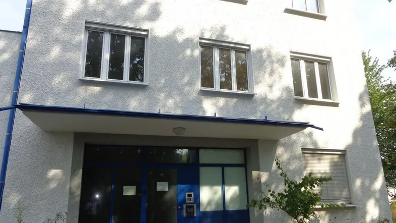 Fassade eines Gebäudes mit mehreren Fenstern und einem blauen Eingangsbereich.