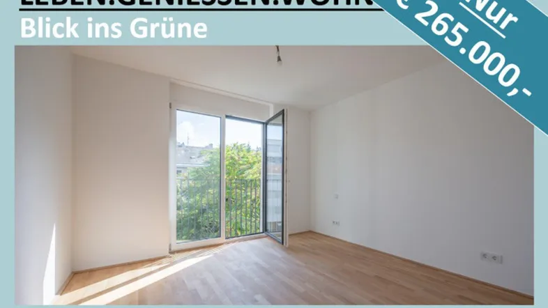 Heller, leerer Raum mit Holzboden, weißen Wänden und großem Fenster mit Blick ins Grüne.