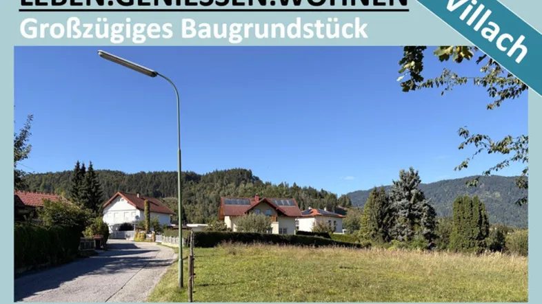 Großzügiges Baugrundstück in Villach, Kärnten, umgeben von Wohnhäusern und grüner Natur mit Bergblick.