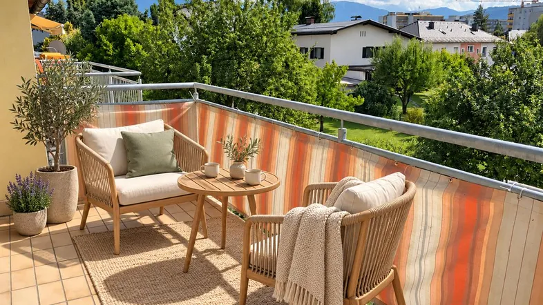 Gemütlicher Balkon mit Sitzgelegenheiten und weitem Blick über die grüne Umgebung und Berge.