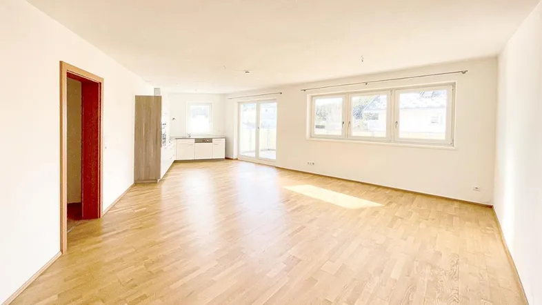 Heller, offener Wohn- und Essbereich mit Parkettboden und Zugang zur Terrasse.