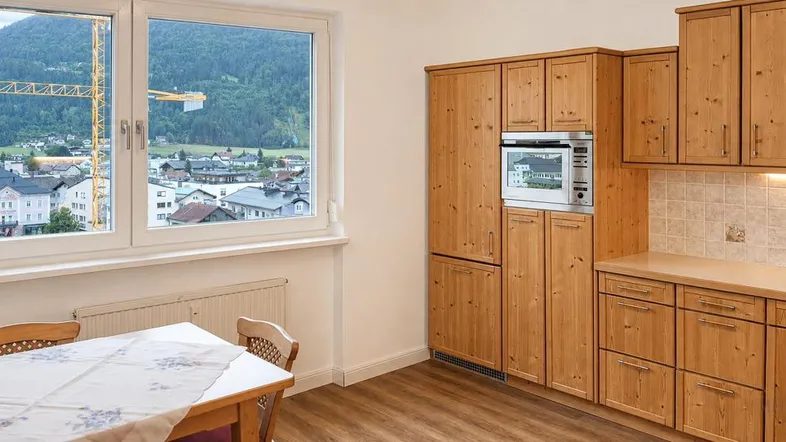 Gemütliche Küche mit Holzeinbauten, Essbereich und Fensterblick auf die umliegende Berglandschaft.