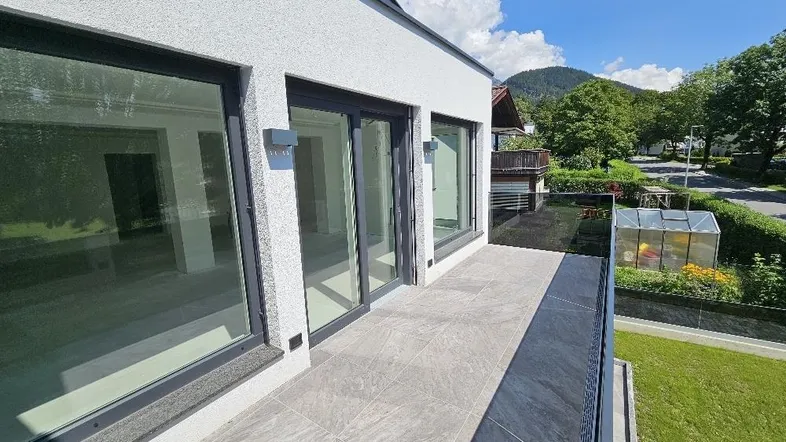 Moderner Balkon mit Fliesenboden und Glasgeländer, bietet einen schönen Blick auf die Umgebung.