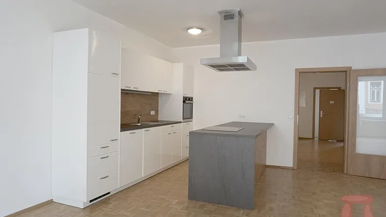 Moderne Einbauküche mit weiß-grauen Fronten, Kochinsel und Parkettboden in einem offenen Wohnbereich.