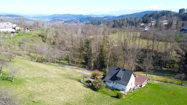 Weitläufige Luftaufnahme eines Hauses in ländlicher Umgebung mit Bergen im Hintergrund.