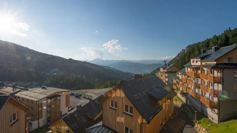 Gebäude in einer alpinen Berglandschaft mit strahlendem Sonnenschein und weitem Blick.