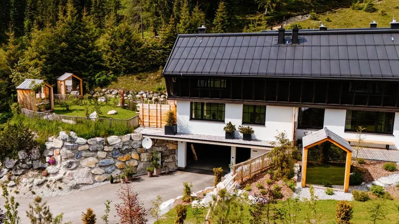 Modernes Gebäude in alpiner Landschaft mit Zufahrt und gepflegter Außenanlage.