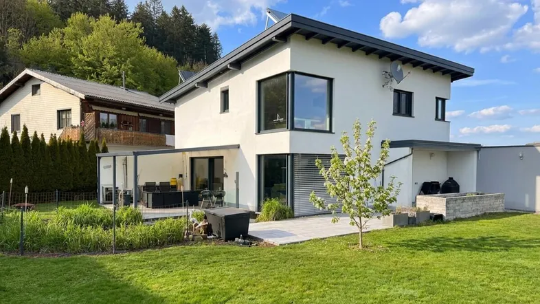 Modernes Einfamilienhaus mit großem Garten, Terrasse und Blick auf die umliegende Natur.