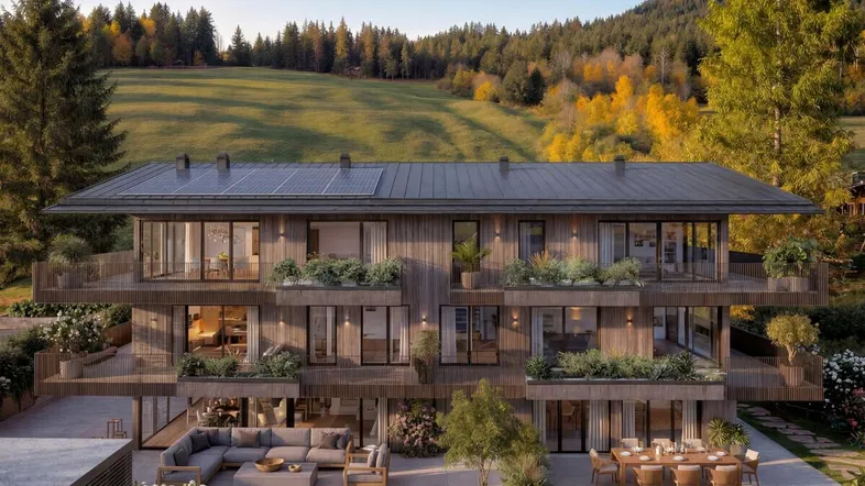Moderne Holzfassade mit Balkonen, Terrassen und Solaranlage, eingebettet in eine grüne Hügellandschaft.